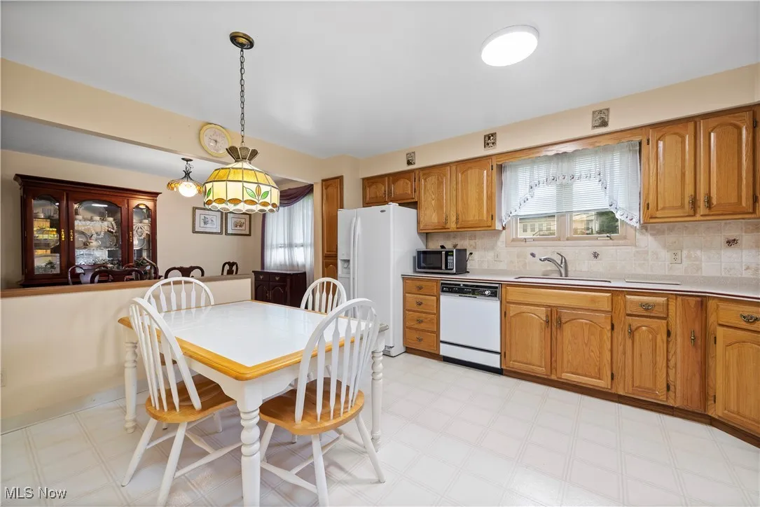 Kitchen featuring light floors, white appliances, brown cabinets, and decorative backsplash