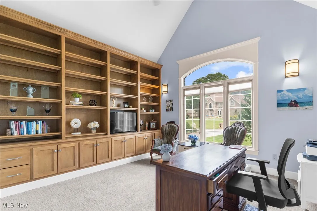 Library style office with floor to ceiling built-ins and high vaulted ceiling