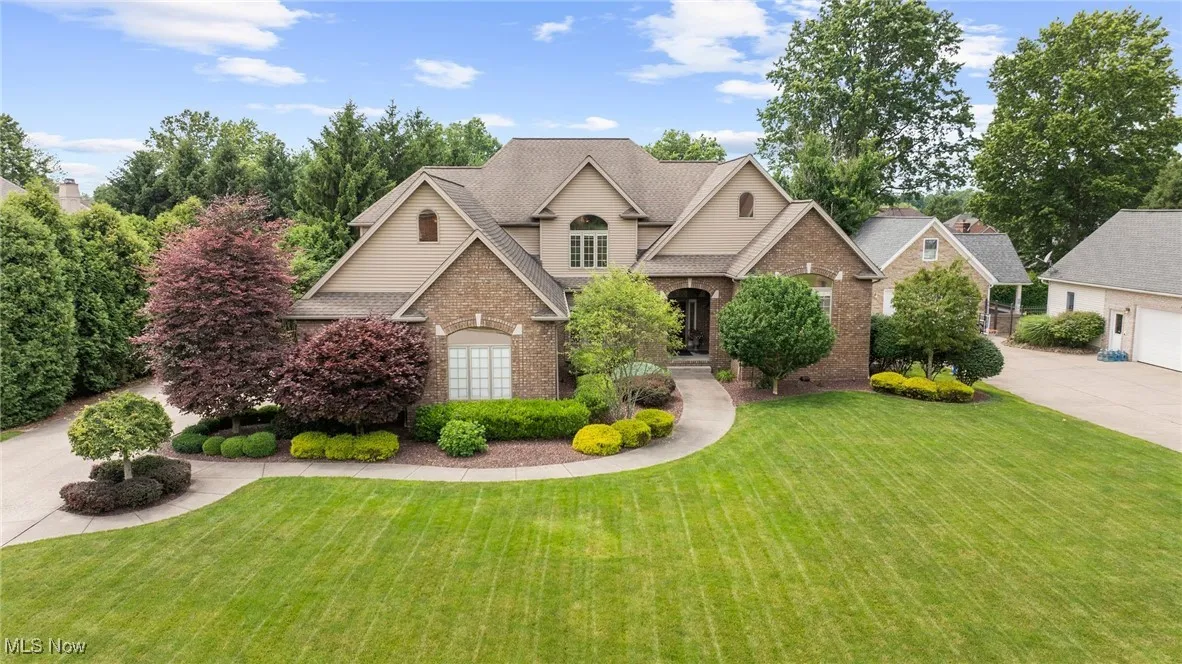 Traditional-style house with brick siding, a front yard, a garage, driveway, and a shingled roof