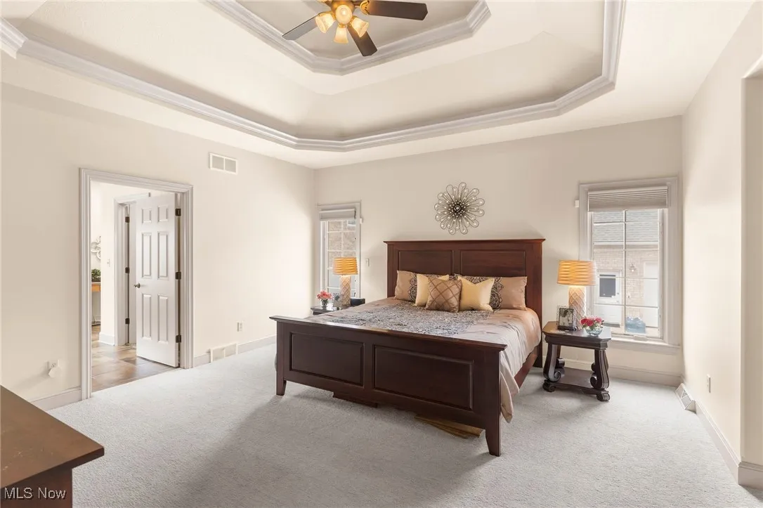 Primary Bedroom featuring a tray ceiling, and a ceiling fan