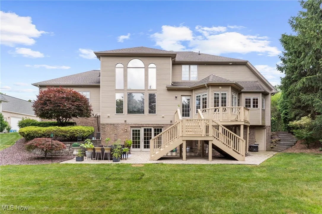 Back of house featuring stairway, a patio, a deck, and a yard