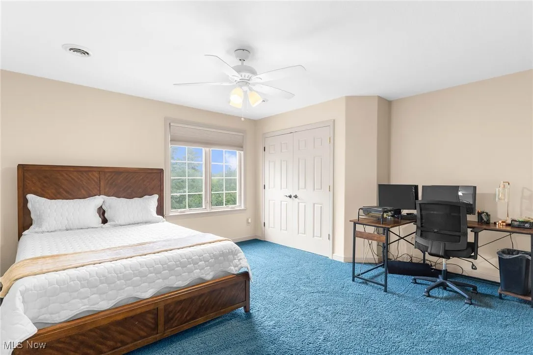 Carpeted bedroom with ceiling fan and closet