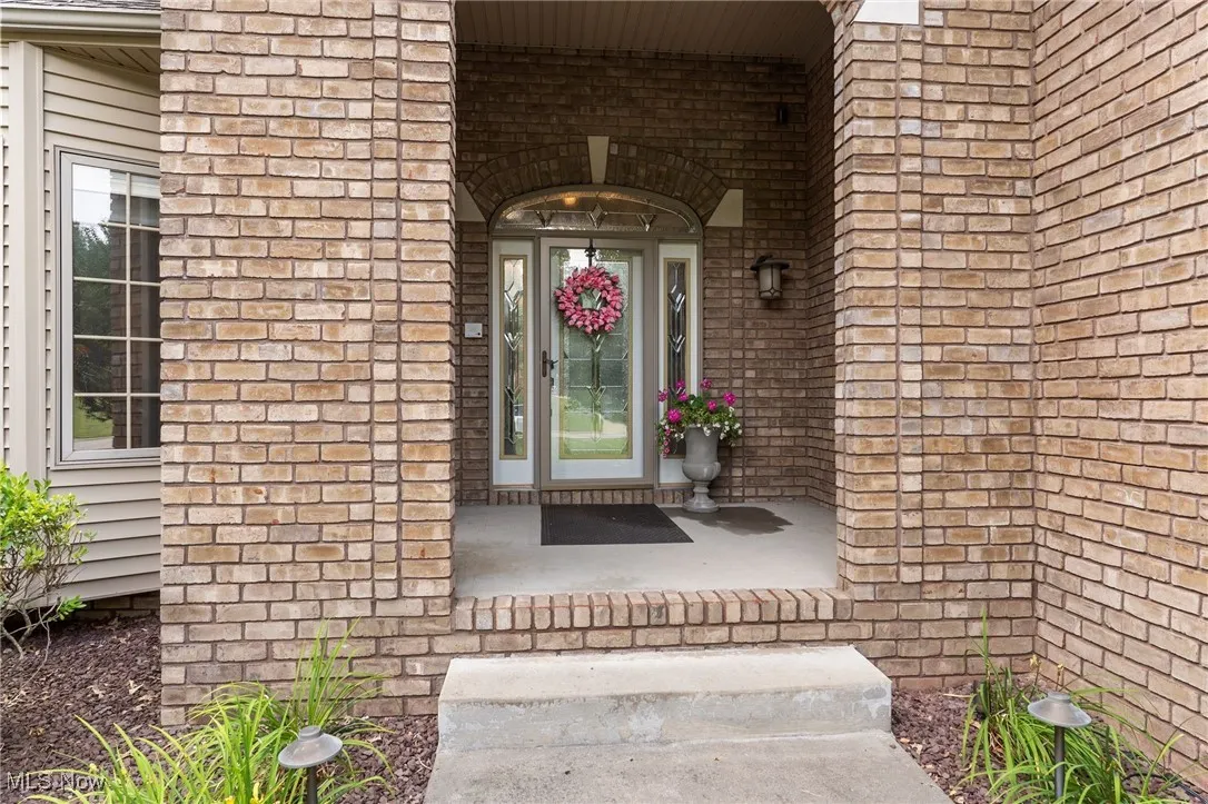 View of exterior entry with brick siding and covered porch