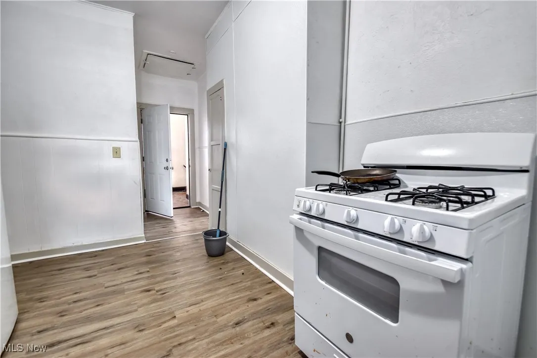 Kitchen with white gas stove and light wood-style flooring