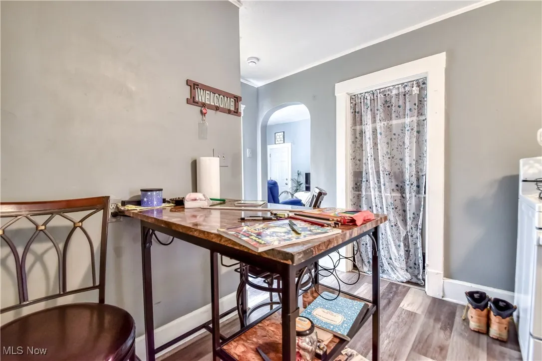 Dining area with arched walkways, wood finished floors, and ornamental molding