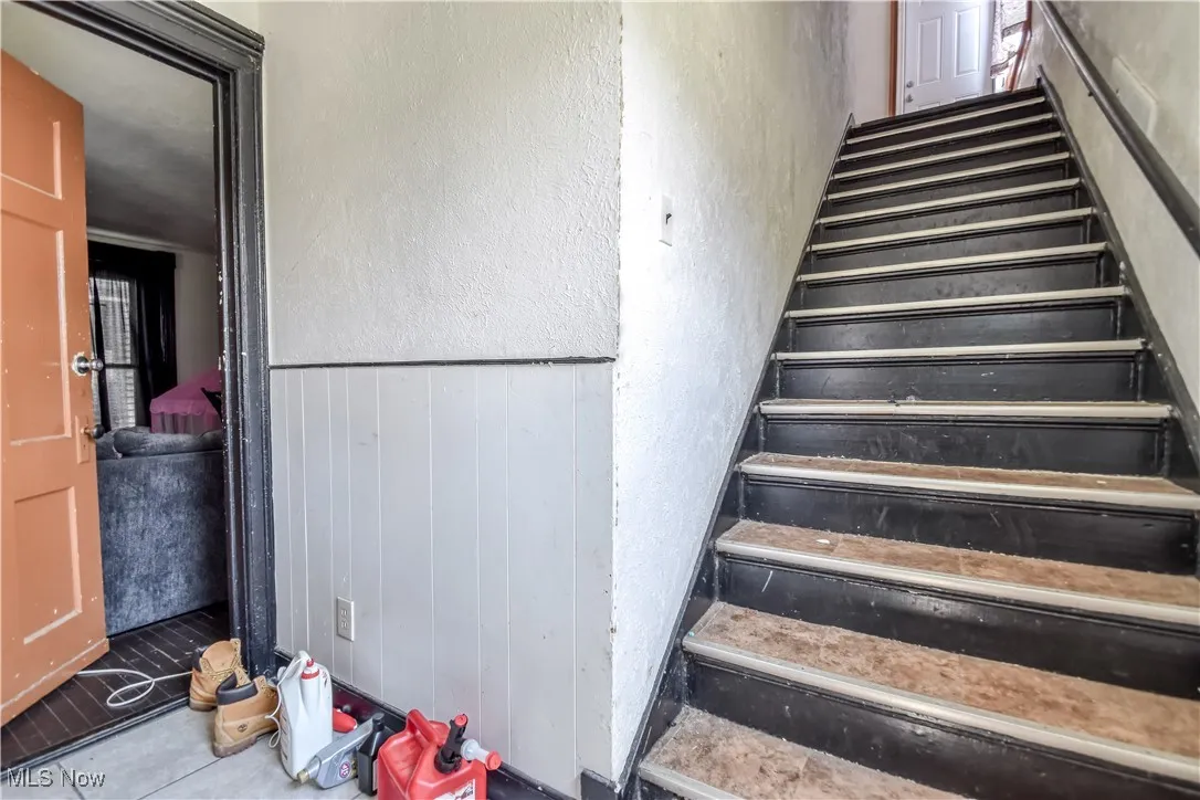 Stairway featuring wainscoting and tile patterned floors