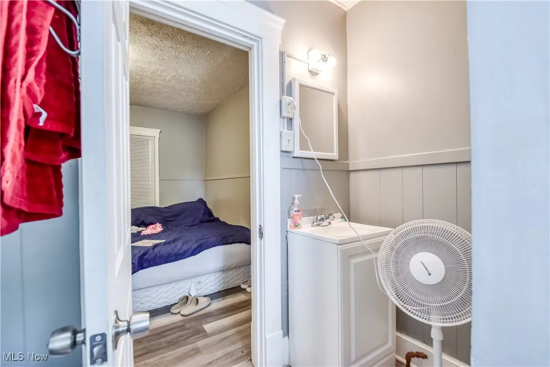 Bathroom with a textured ceiling, wood finished floors, and vanity