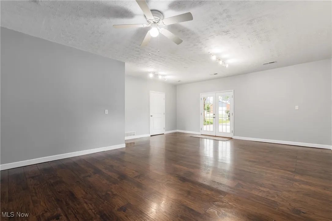 Unfurnished room with a textured ceiling, a ceiling fan, and wood finished floors