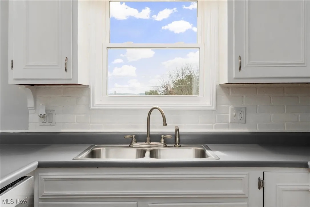 Kitchen featuring dark countertops, white cabinetry, and tasteful backsplash