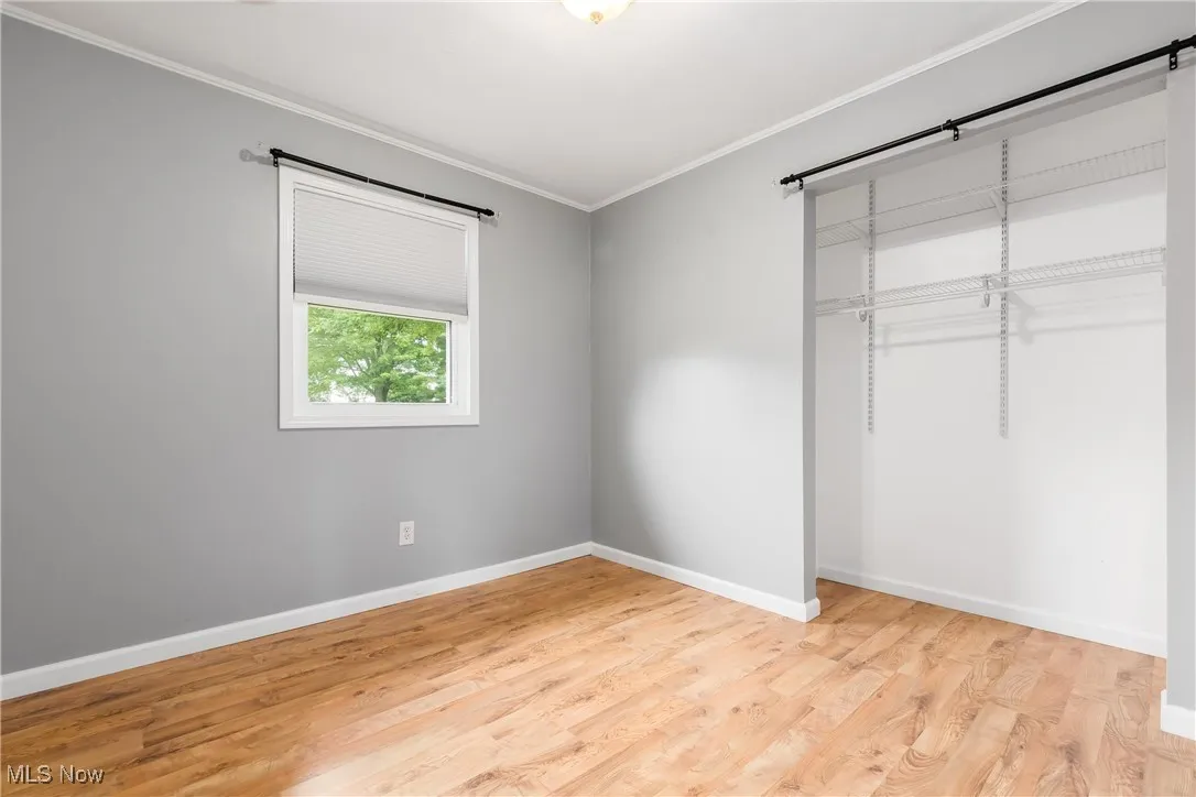 Unfurnished bedroom featuring a closet, crown molding, and light wood-style floors