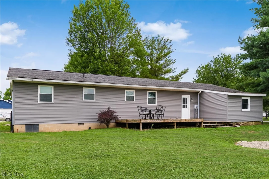 Rear view of house with a wooden deck, crawl space, and a shingled roof