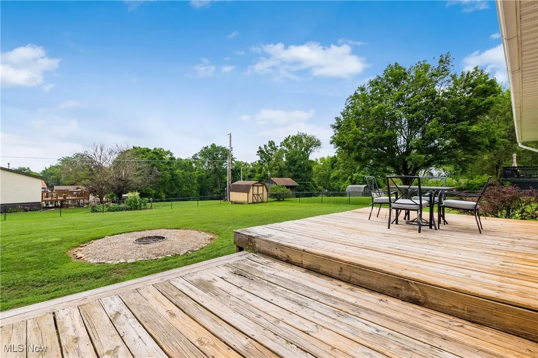 Deck with a fire pit, a storage shed, a fenced backyard, and outdoor dining space