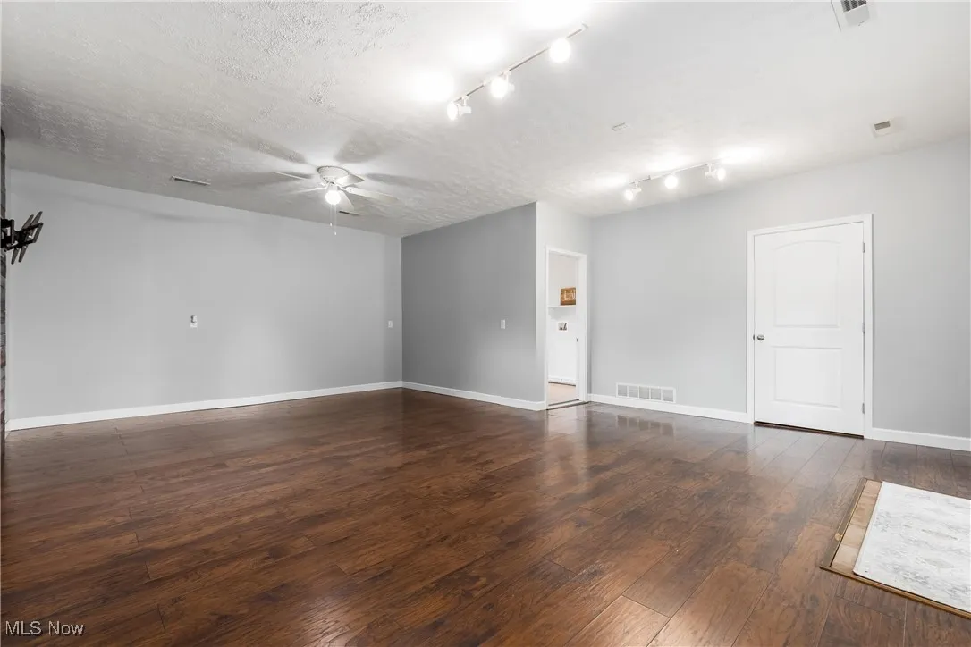 Empty room featuring ceiling fan, hardwood / wood-style floors, and a textured ceiling