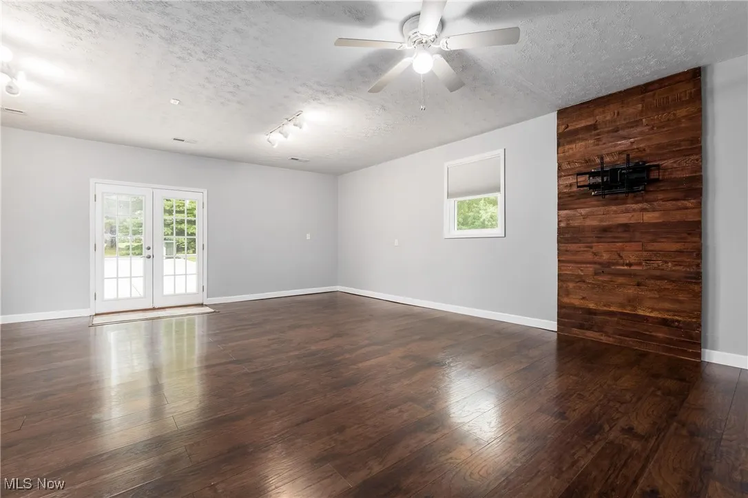Spare room with a textured ceiling, dark wood-style floors, and a ceiling fan