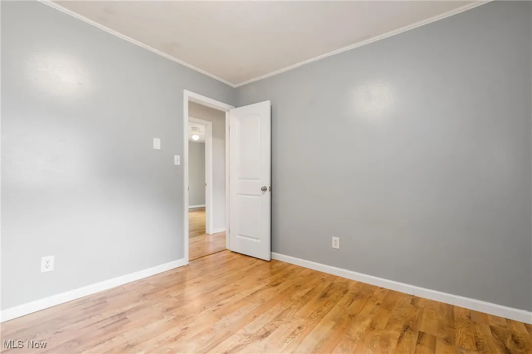 Unfurnished room featuring light wood-style flooring and crown molding