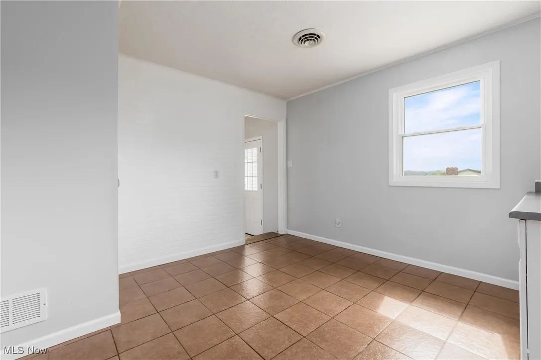 Unfurnished room with light tile patterned flooring and crown molding