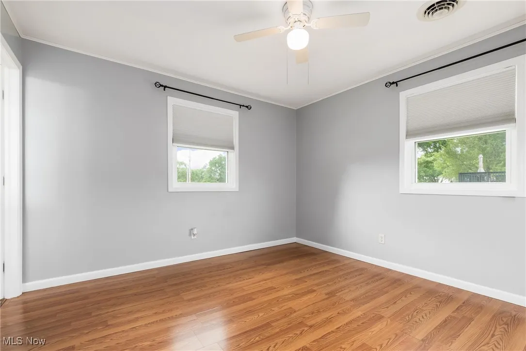Unfurnished room featuring ornamental molding, light wood finished floors, and a ceiling fan