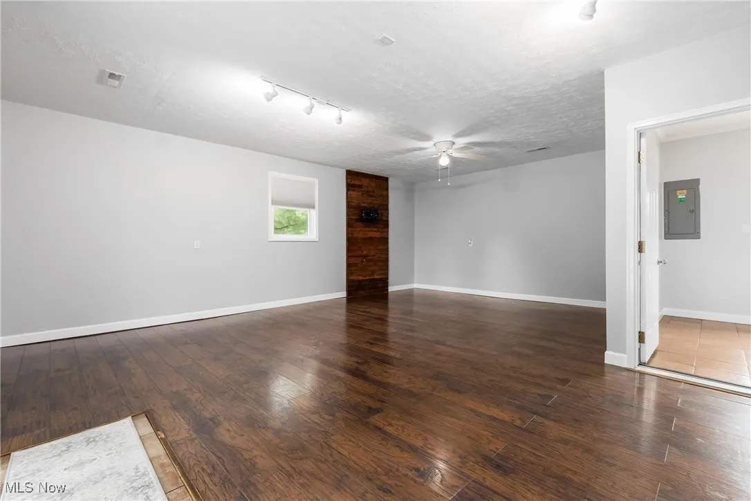 Unfurnished room with ceiling fan, electric panel, wood finished floors, a textured ceiling, and track lighting