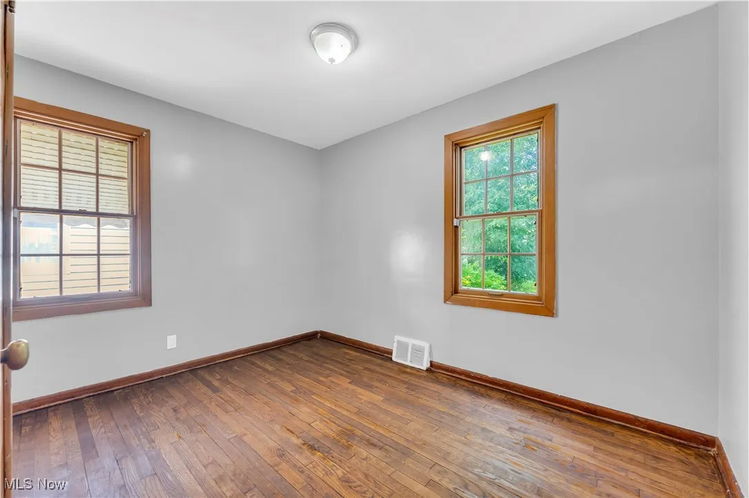 Empty room featuring dark wood finished floors and baseboards
