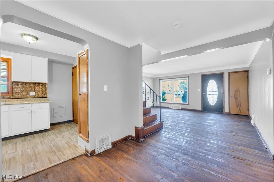 Kitchen featuring hardwood / wood-style floors, white cabinets, decorative backsplash, open floor plan, and light stone countertops