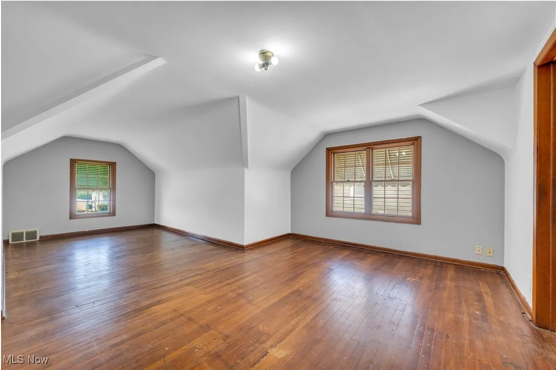 Bonus room with plenty of natural light, lofted ceiling, and wood-type flooring