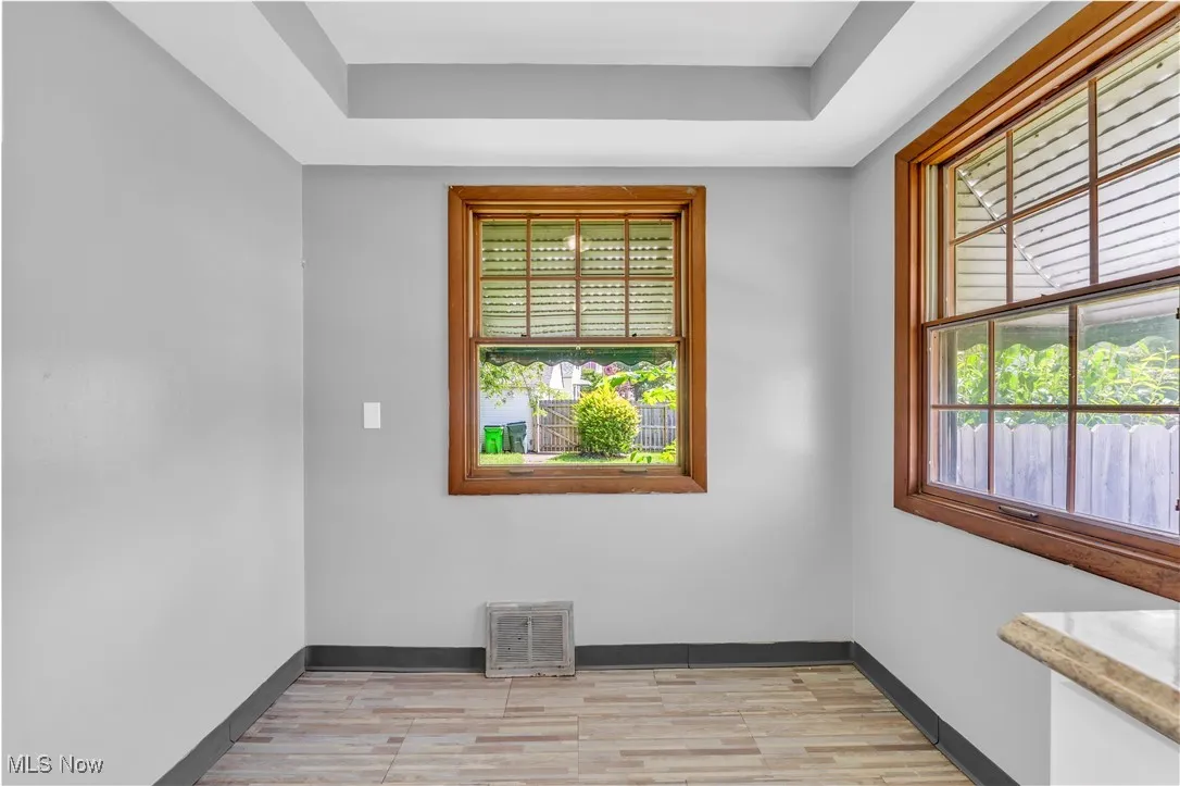Empty room with light wood-type flooring and a tray ceiling