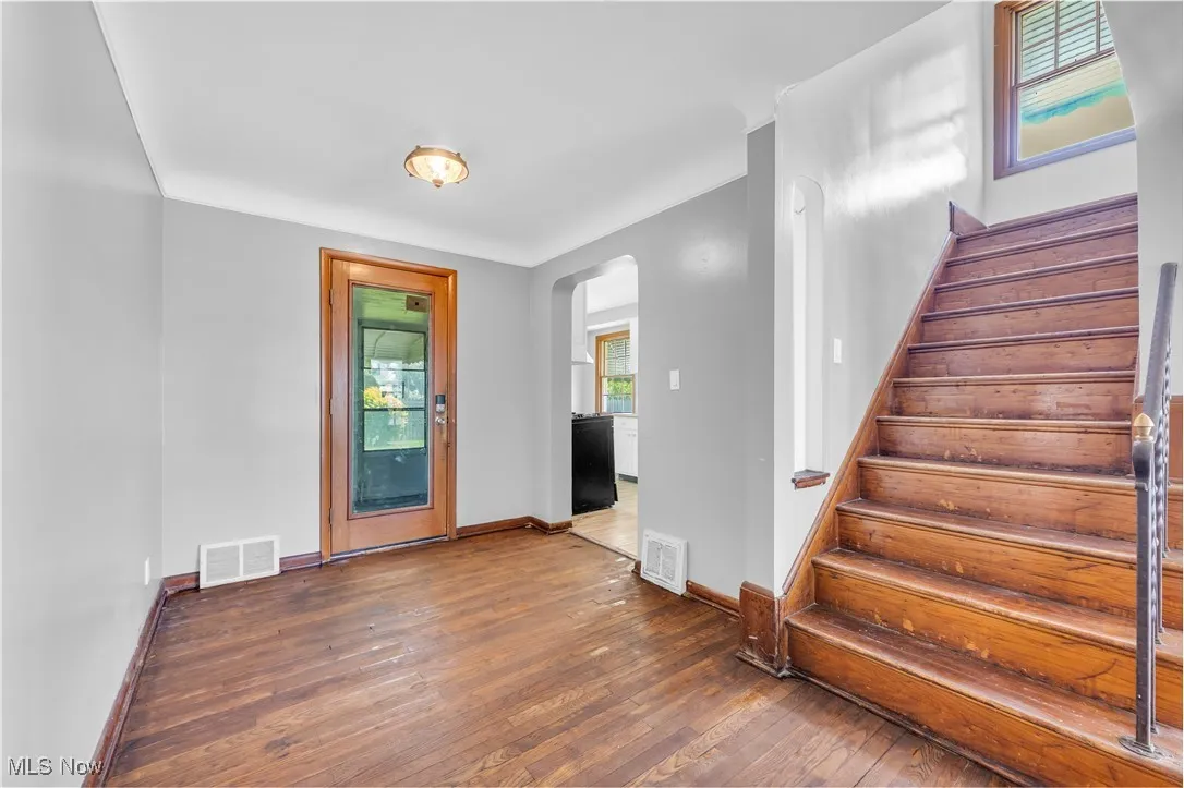 Entrance foyer featuring arched walkways, wood-type flooring, and stairway