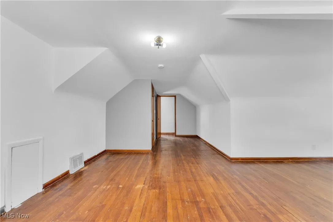 Bonus room with hardwood / wood-style floors and vaulted ceiling