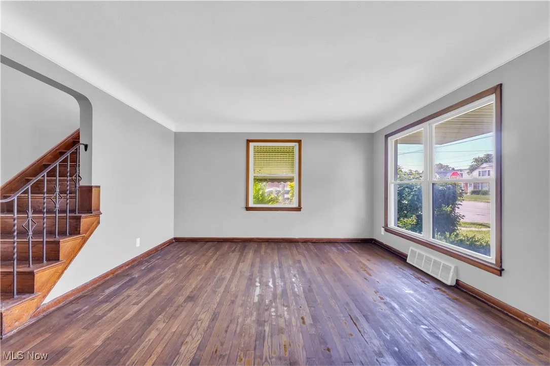 Unfurnished living room featuring hardwood / wood-style flooring, stairs, and arched walkways