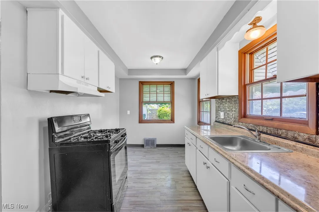 Kitchen featuring black gas stove, white cabinetry, and light wood finished floors