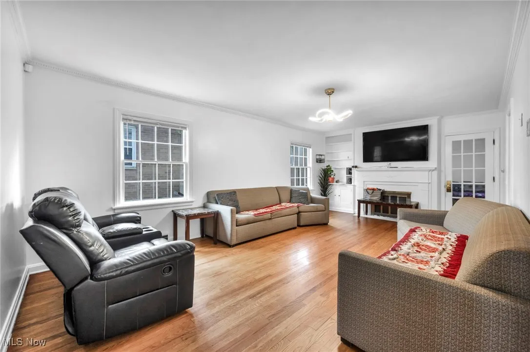 Living room featuring ornamental molding, a chandelier, and wood finished floors