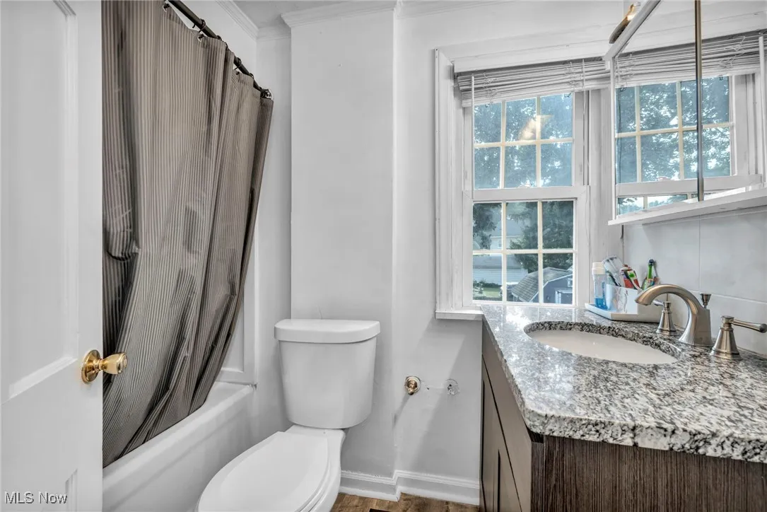Bathroom with vanity, shower / tub combo, and ornamental molding