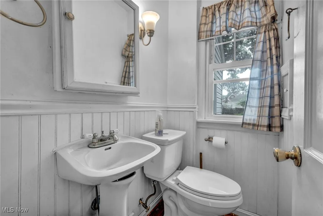 Half bath featuring a wainscoted wall and toilet