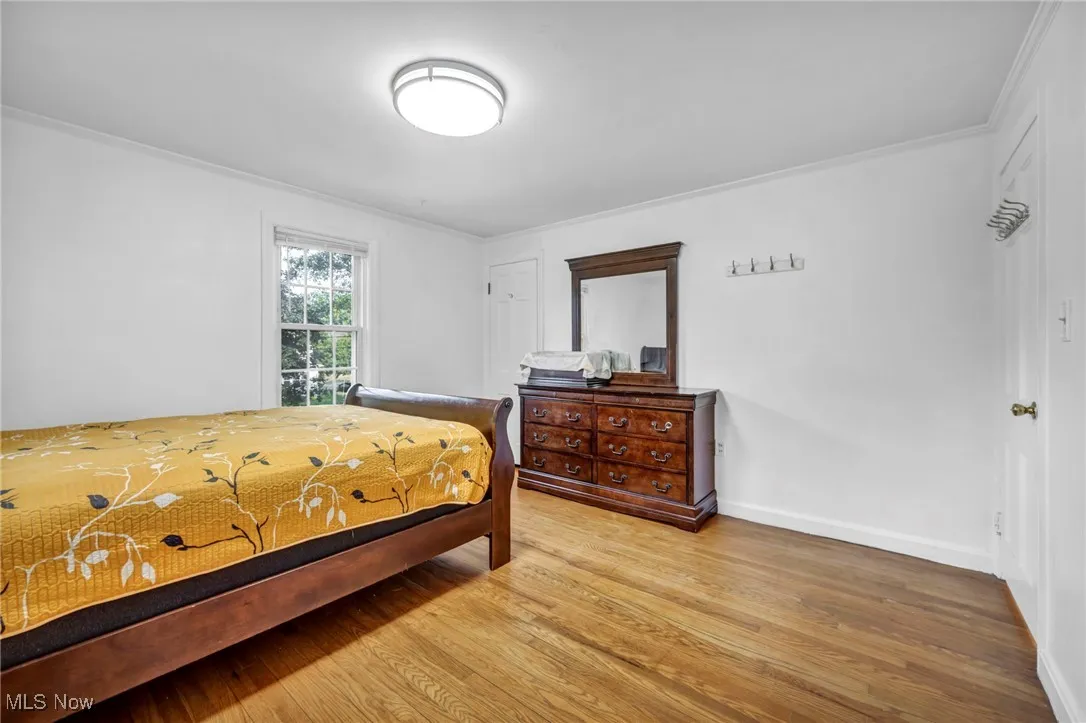 Bedroom with light wood-style floors and crown molding