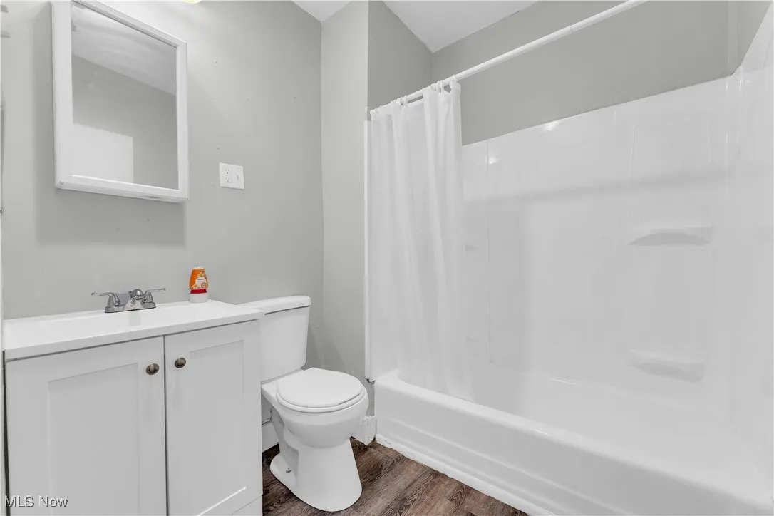 Bathroom with vanity, wood finished floors, and shower / bath combo with shower curtain