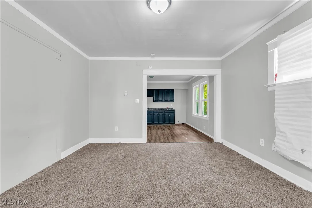 Unfurnished living room with dark carpet and crown molding