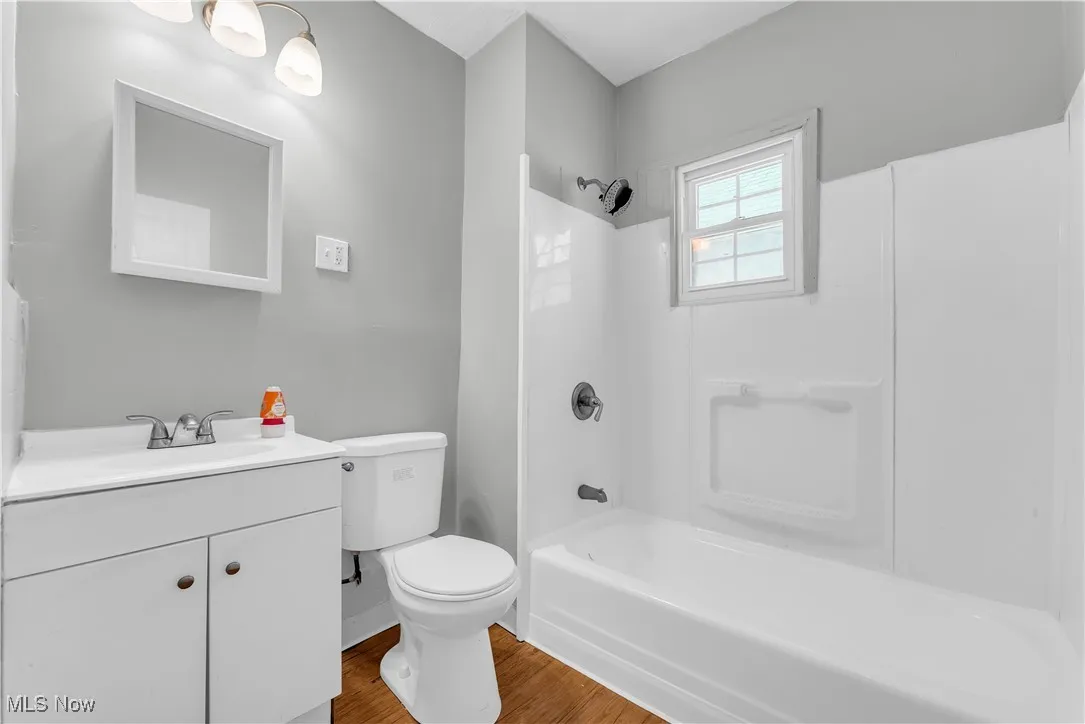 Bathroom with vanity, wood finished floors, and washtub / shower combination
