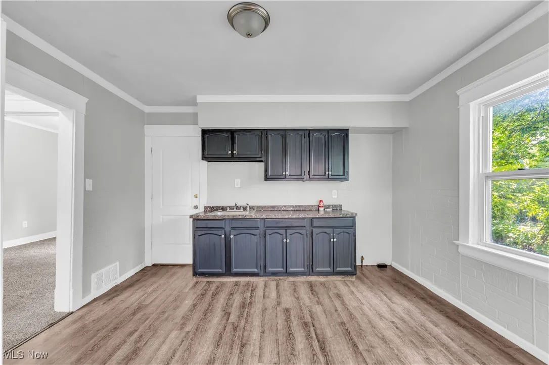 Kitchen with healthy amount of natural light, light wood finished floors, and ornamental molding