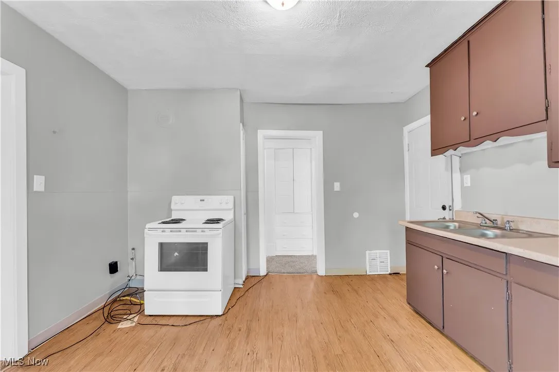 Kitchen with white electric range oven, light wood-style floors, and light countertops
