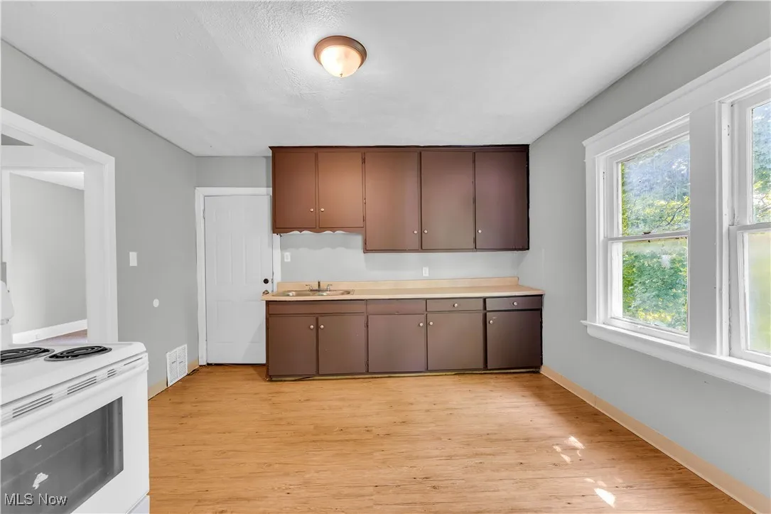 Kitchen with white range with electric stovetop, light wood-type flooring, and light countertops