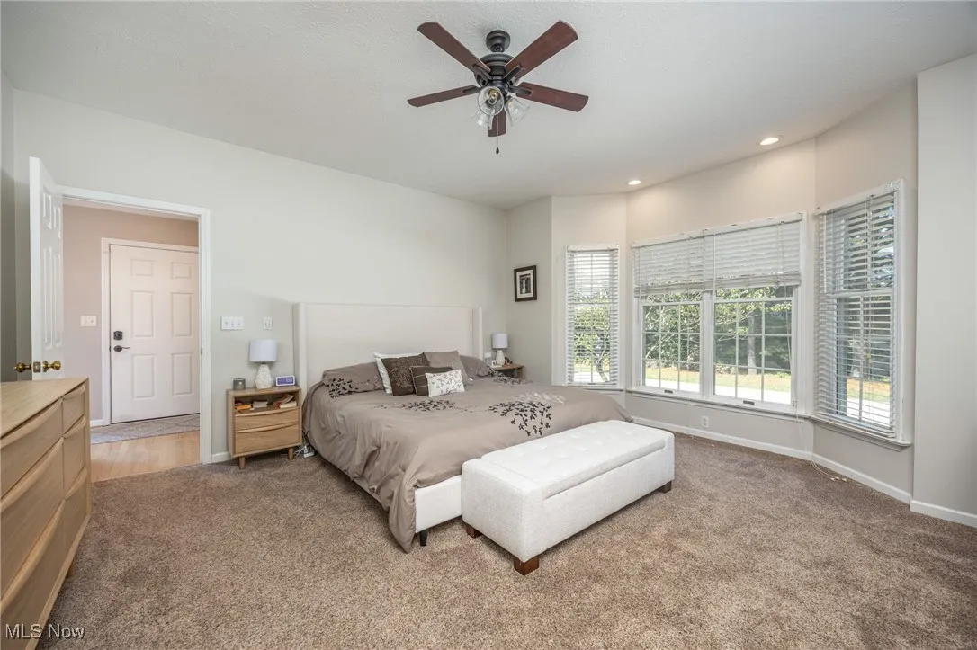 Primary bedroom featuring light colored carpet, recessed lighting, and ceiling fan