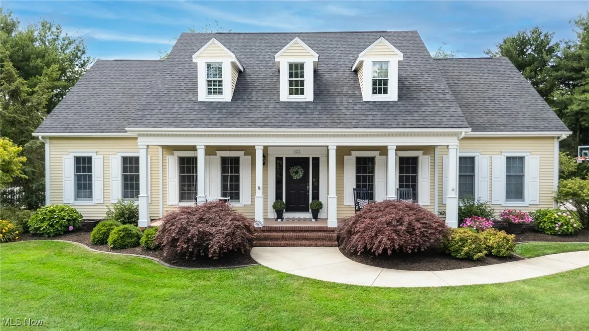 Cape cod home with covered porch, a front yard, and a shingled roof
