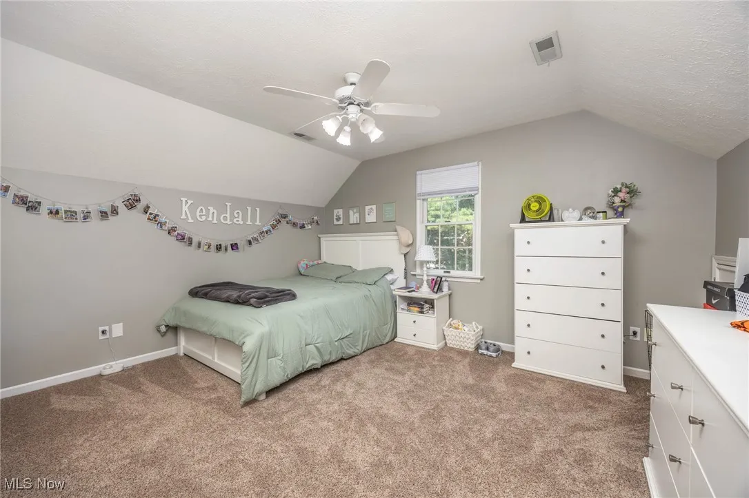 Bedroom featuring carpet, vaulted ceiling, and a ceiling fan