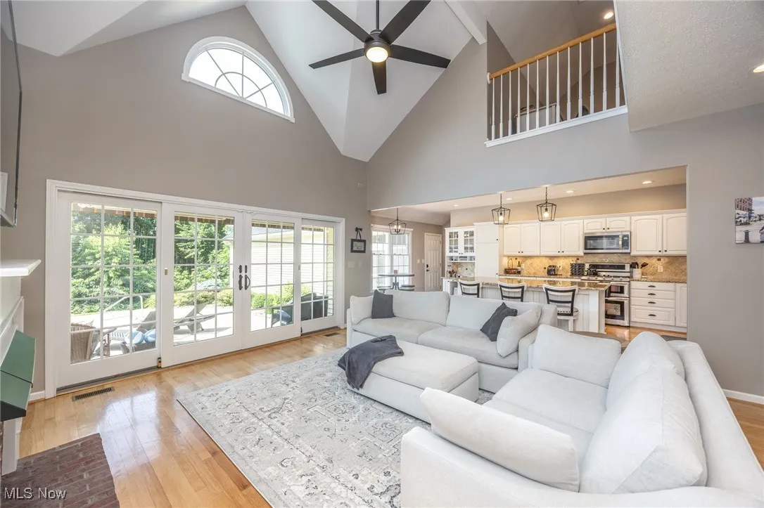 Living area with ceiling fan, light wood-style floors, high vaulted ceiling, and french doors
