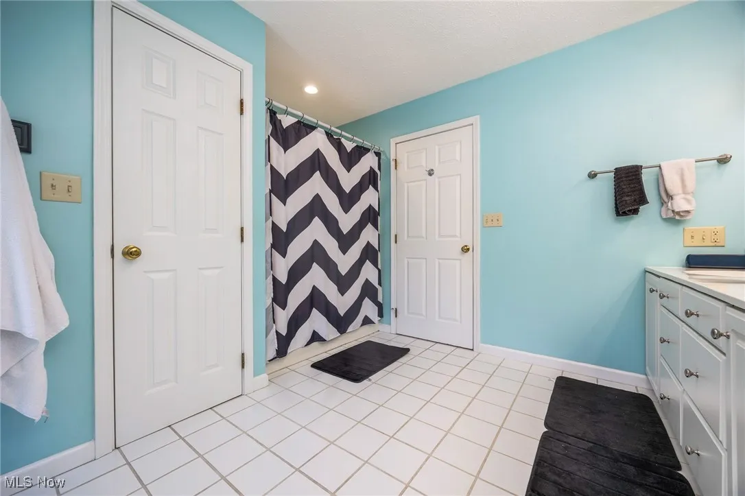Full bath featuring vanity, tile patterned flooring, recessed lighting, and a shower with curtain