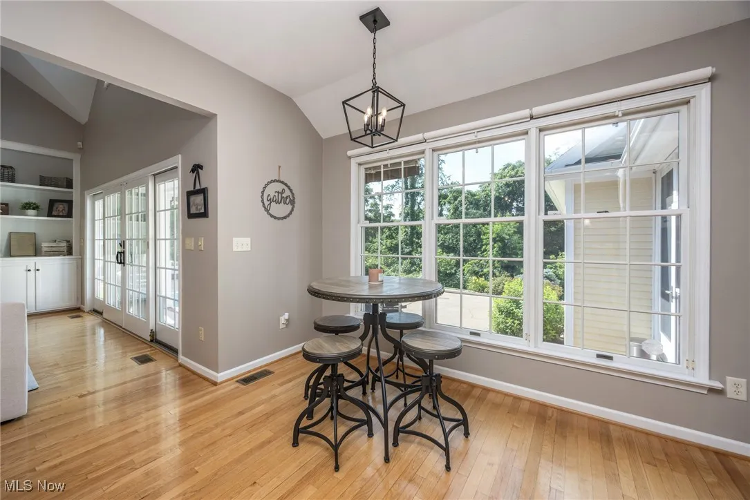 Eat-in kitchen dining space featuring lofted ceiling, a chandelier, plenty of natural light, and light hardwood flooring