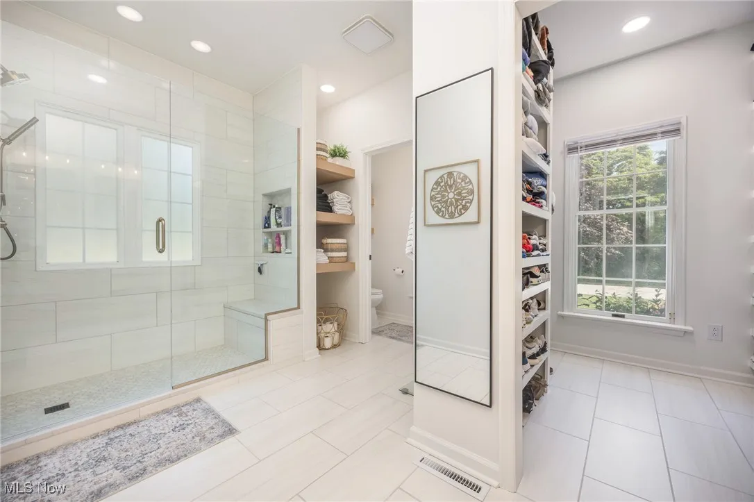 Primary bathroom with a shower stall, recessed lighting, a walk in closet, and tile patterned floors