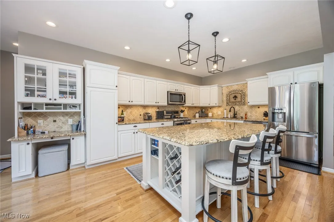Kitchen with appliances with stainless steel finishes, white cabinetry, a kitchen bar, a kitchen island, and recessed lighting