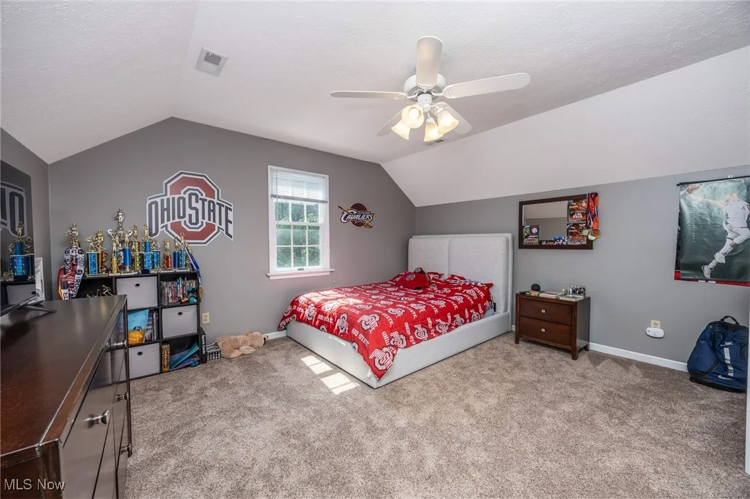 Bedroom featuring lofted ceiling, carpet floors, a ceiling fan, and a textured ceiling