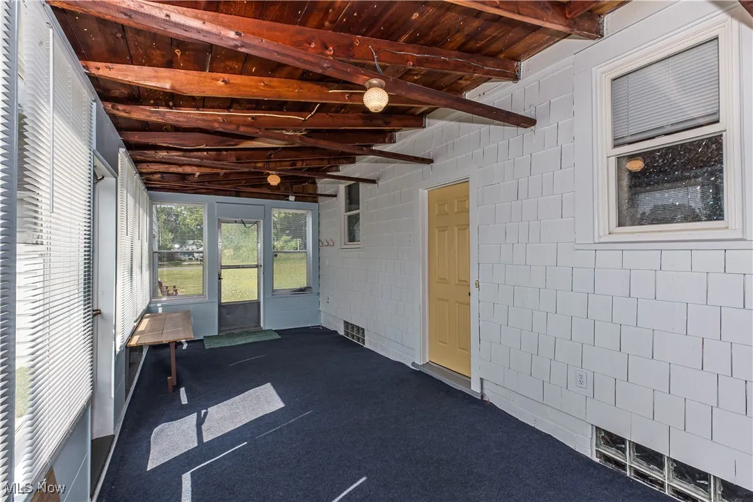 Unfurnished sunroom featuring beam ceiling